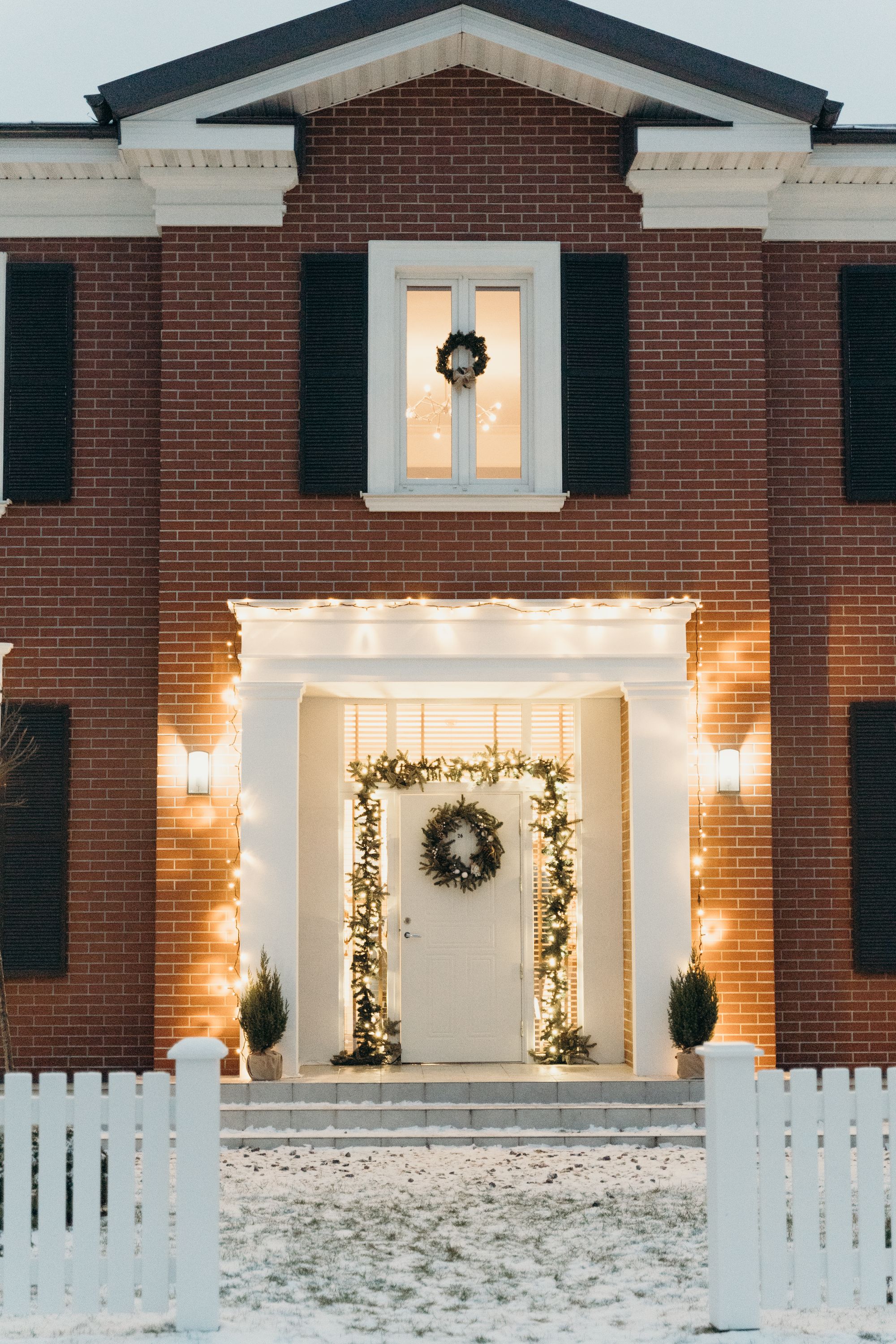 Warm white holiday lights around a brick home's entrance in winter